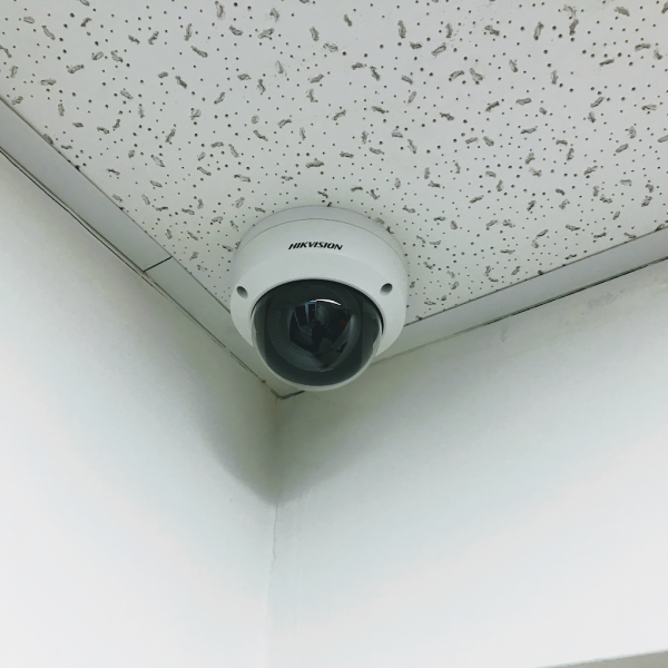 Фото Монтаж купольної IP-камери Hikvision на стелі для внутрішнього відеоспостереження. Акуратне встановлення в куті приміщення для контролю робочої зони.